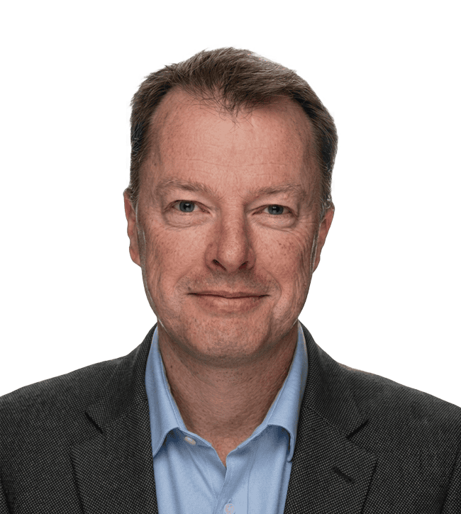 Professional headshot of a smiling man in a dark blazer and light blue shirt looking at the camera